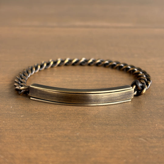Brass bracelet with a flat tag on a wooden surface