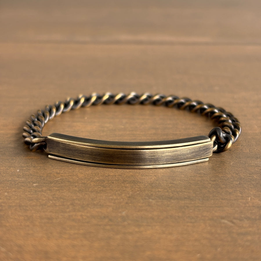 Brass bracelet with a flat tag on a wooden surface