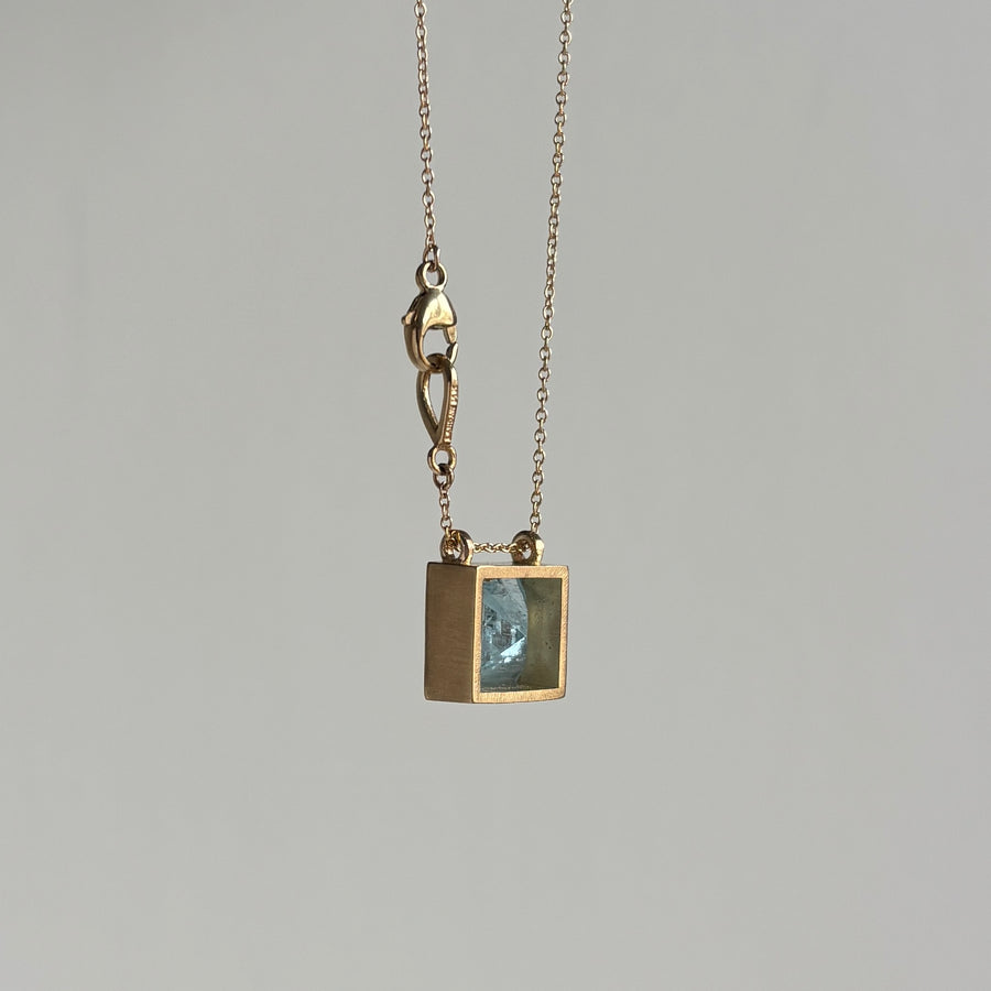 Gold necklace with a pendant on a gray background side view