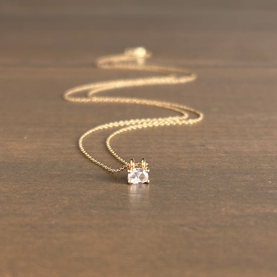 Gold necklace with a diamond pendant on a wooden surface