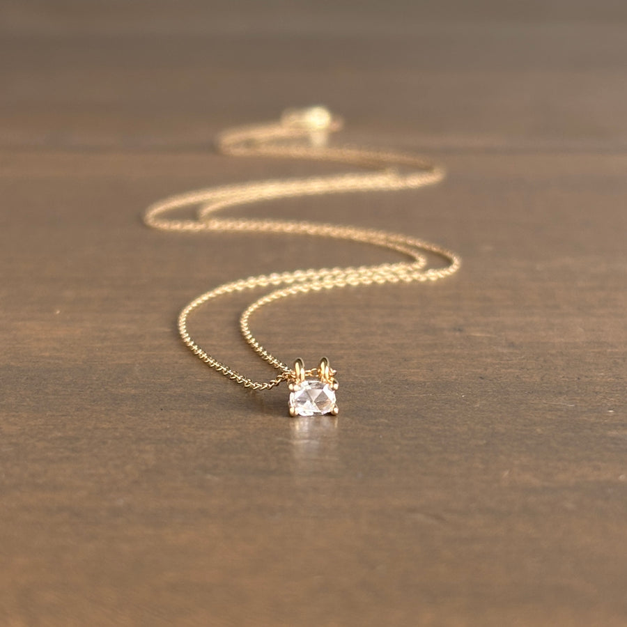 Gold necklace with a diamond pendant on a wooden surface