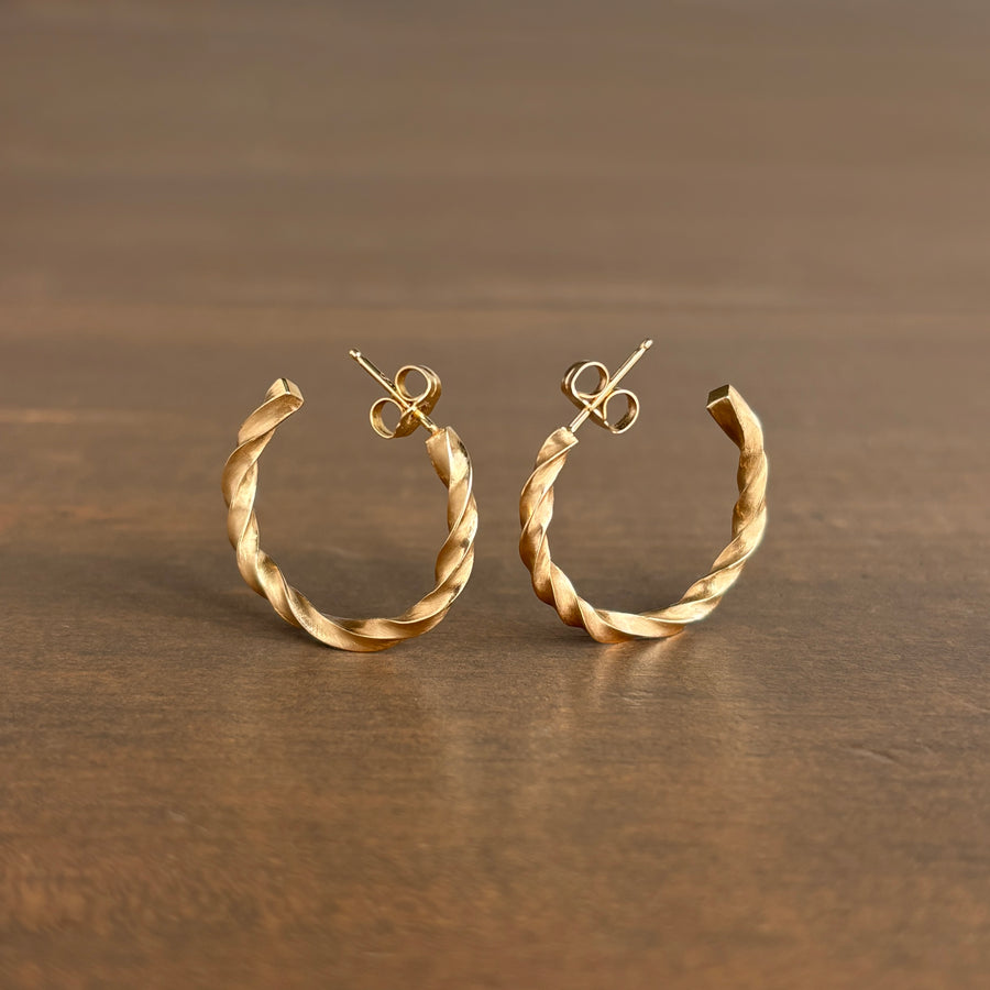 Gold hoop earrings on a wooden surface