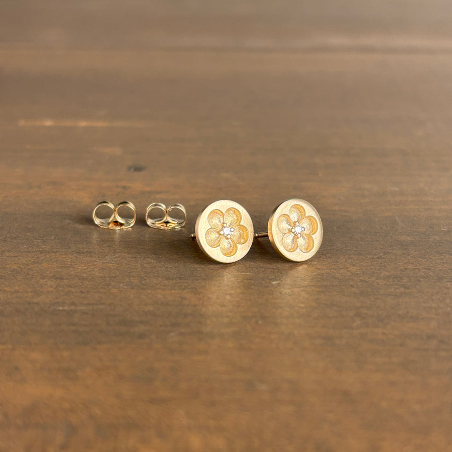 Gold floral earrings on a wooden surface