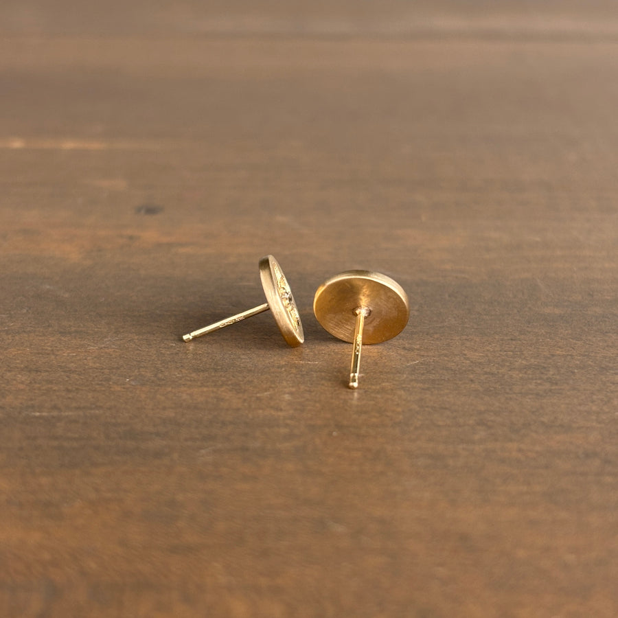 Gold stud earrings on a wooden surface