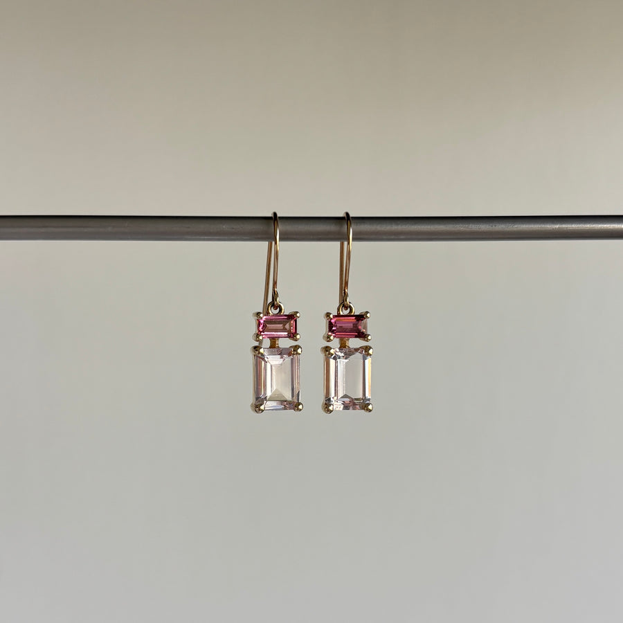 Pair of earrings with pink gemstones on a gray background hanging