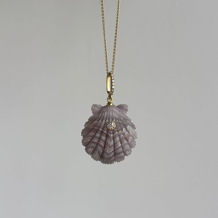 Shell-shaped pendant on a gold chain against a gray background