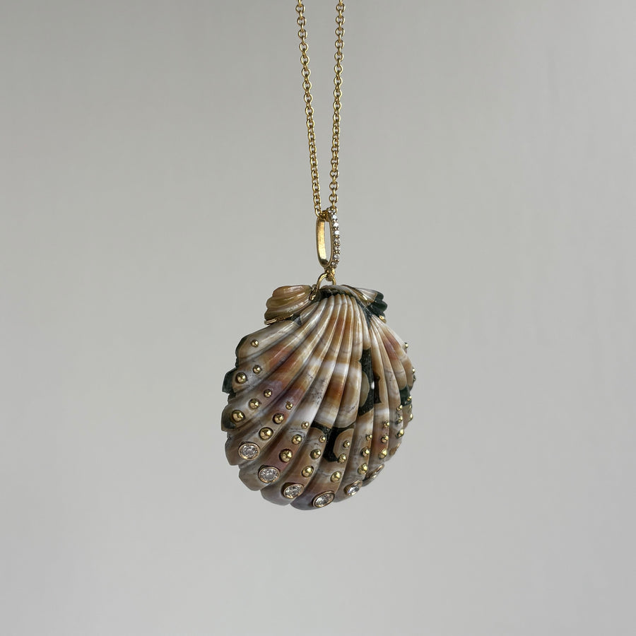 Shell-shaped pendant with embedded stones on a gold chain against a gray background
