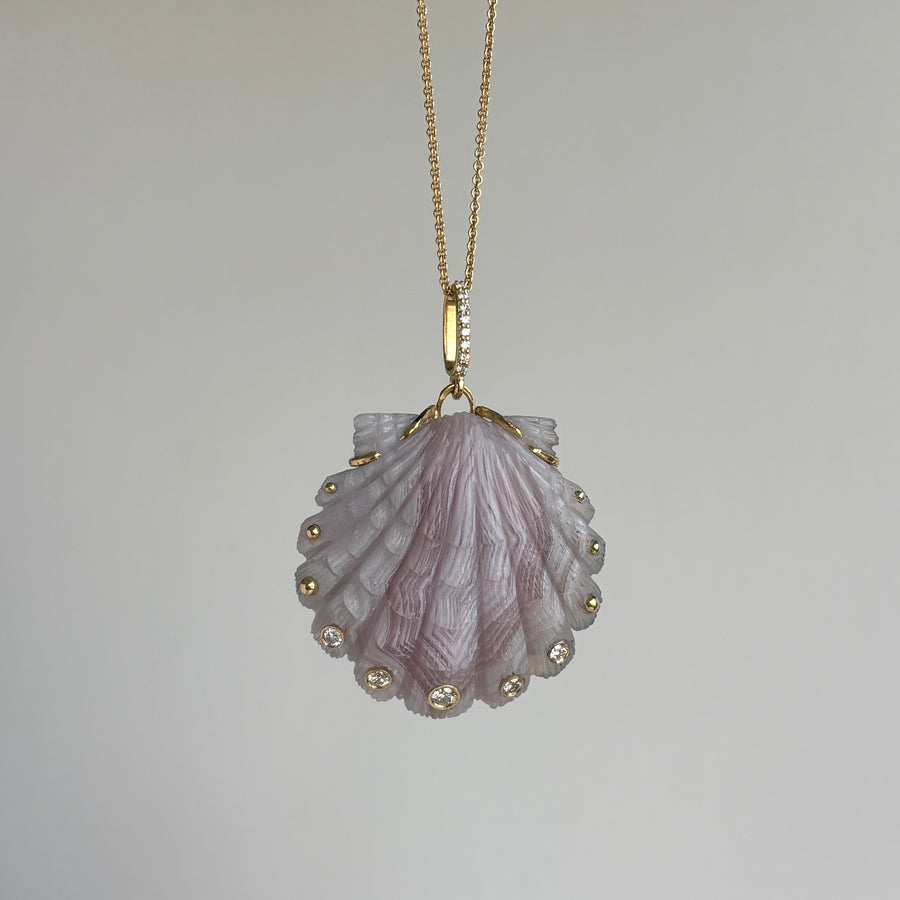 Shell-shaped pendant with gold accents on a chain against a gray background