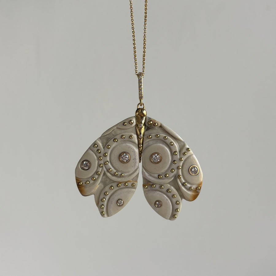 Decorative moth-shaped pendant on a chain against a gray background