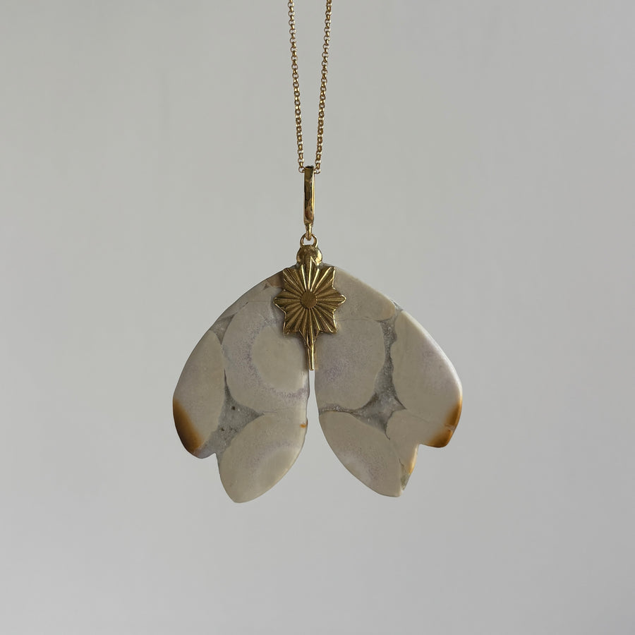 Necklace with a pendant featuring two leaf-shaped stones on a plain background