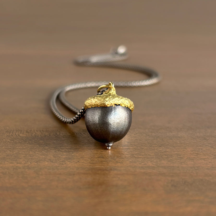 Necklace with a acorn pendant on a wooden surface