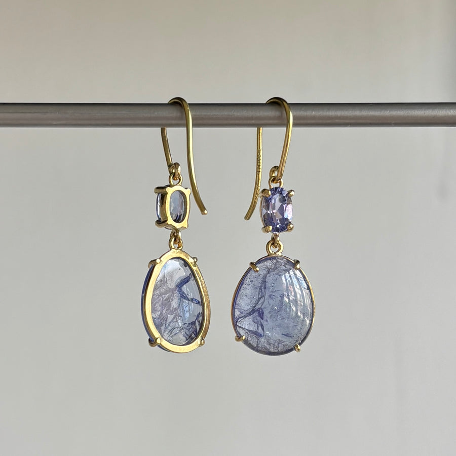 Pair of gold earrings with blue gemstones on a gray background back view