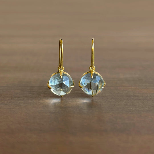Gold earrings with blue gemstones on a wooden surface