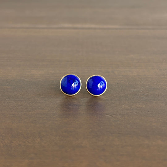 Pair of blue round earrings on a wooden surface