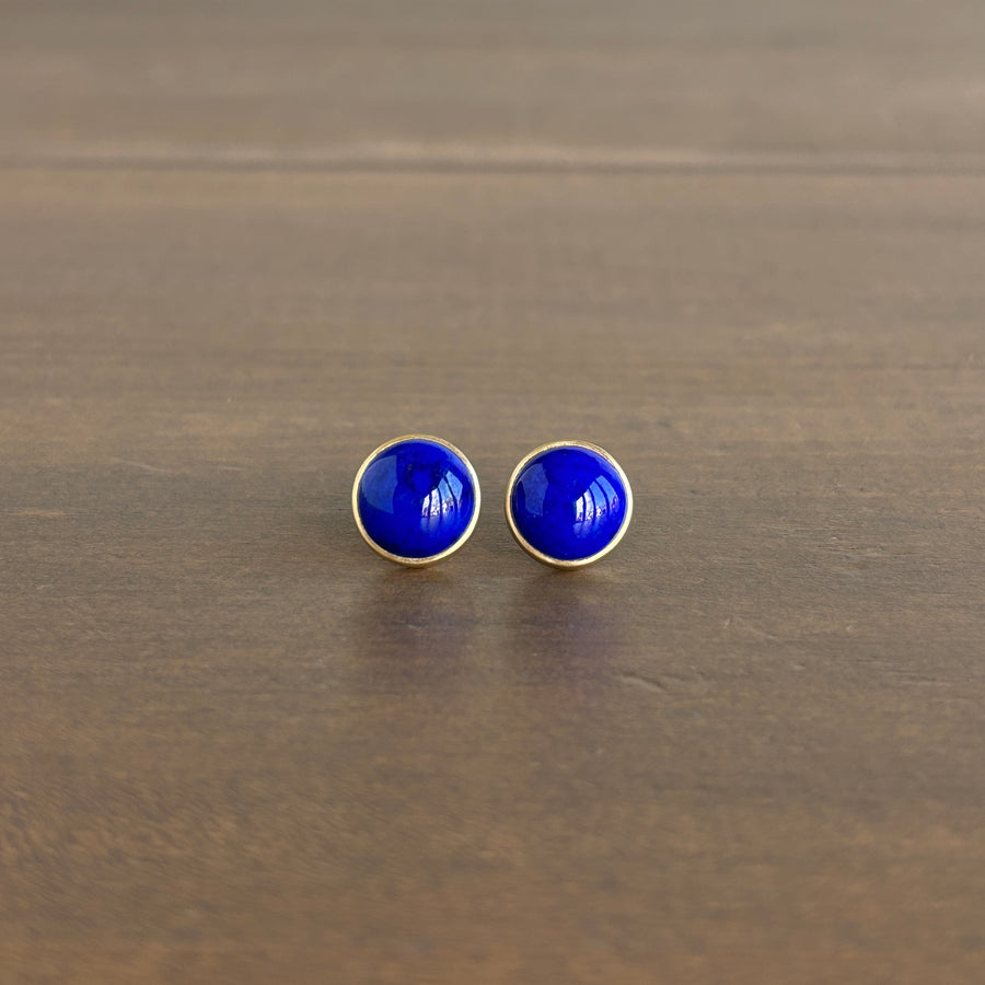 Pair of blue round earrings on a wooden surface
