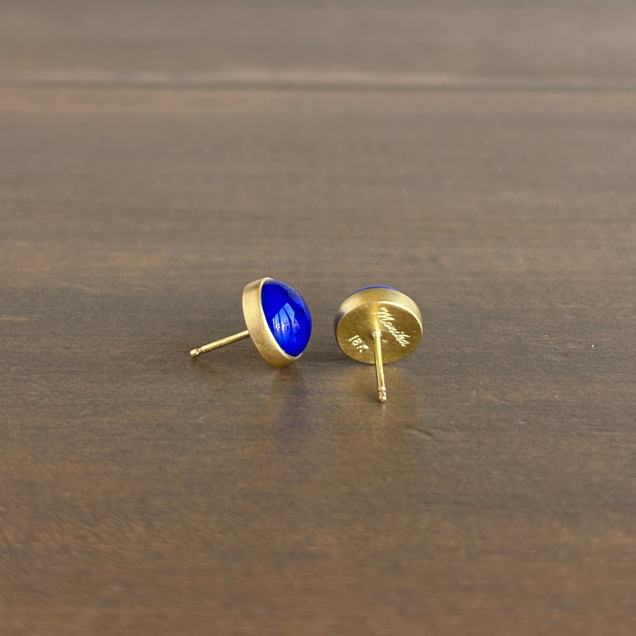Gold earrings with blue stones on a wooden surface