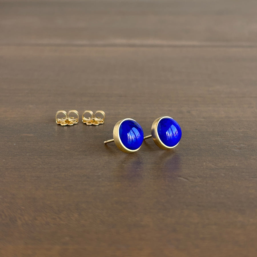 Gold earrings with blue stones on a brown surface