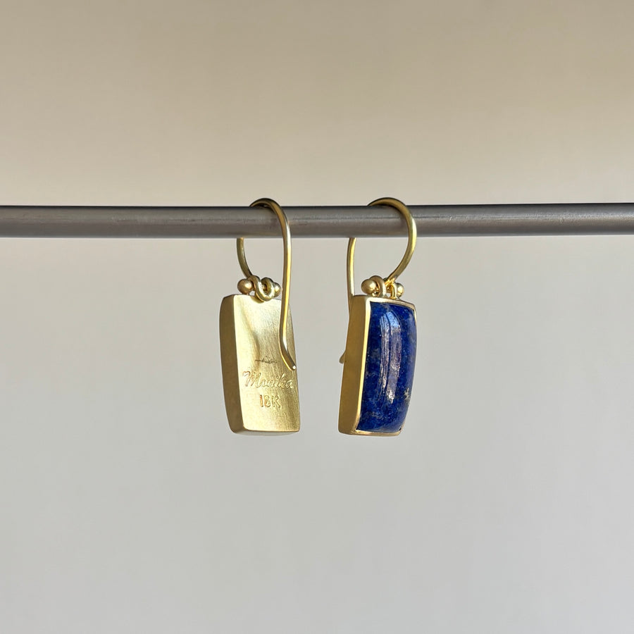 Gold earrings with blue stones on a gray background