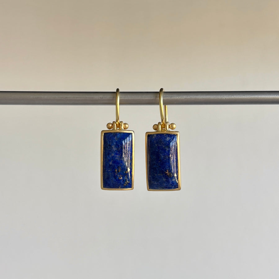 Gold earrings with blue stones on a gray background