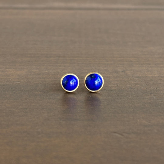 Pair of blue round earrings on a wooden surface