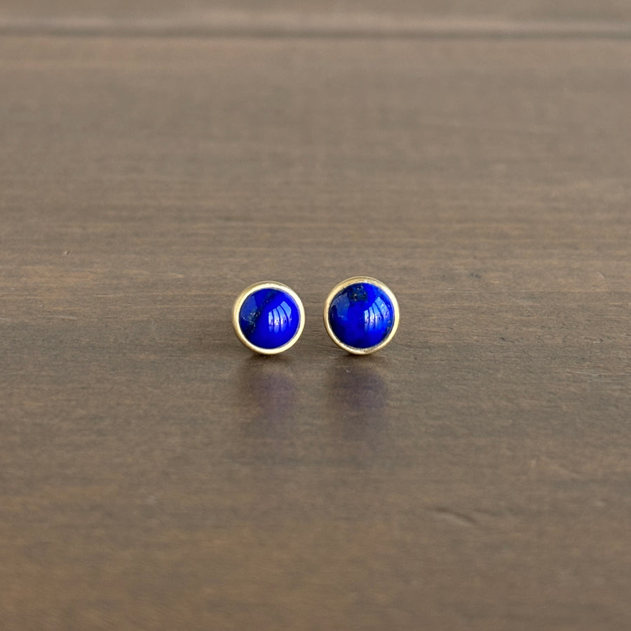 Pair of blue round earrings on a wooden surface