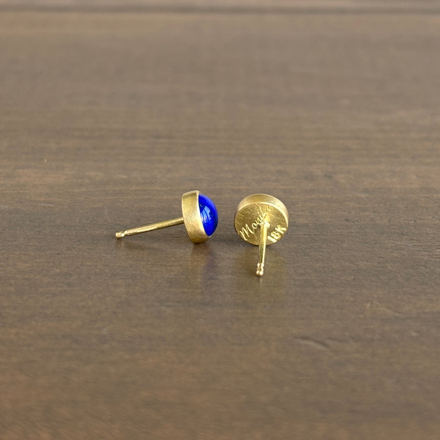 Gold earrings with blue gemstones on a wooden surface