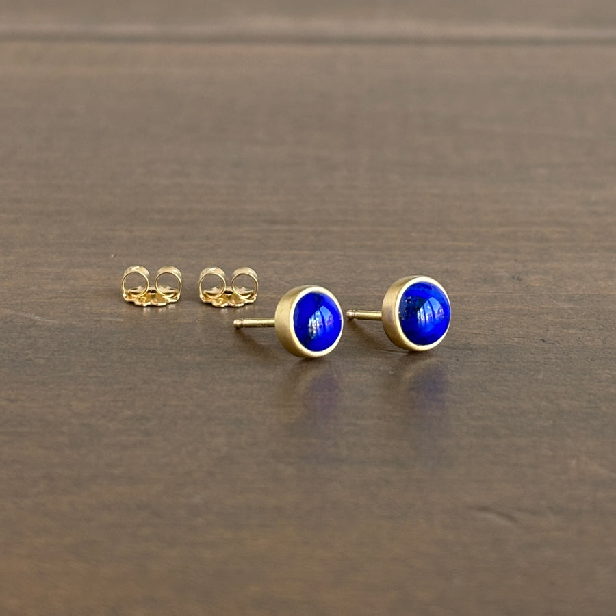 Gold earrings with blue stones on a brown surface
