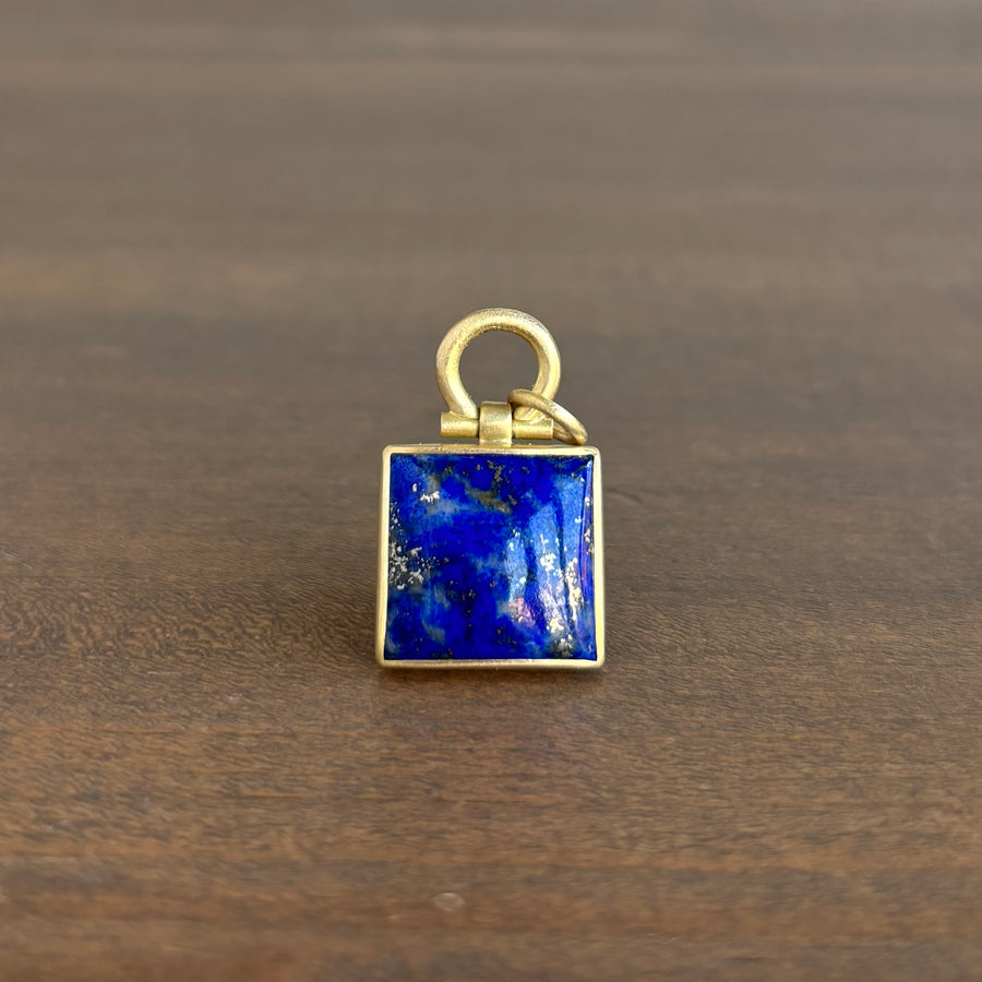 Gold pendant with a blue stone on a wooden surface