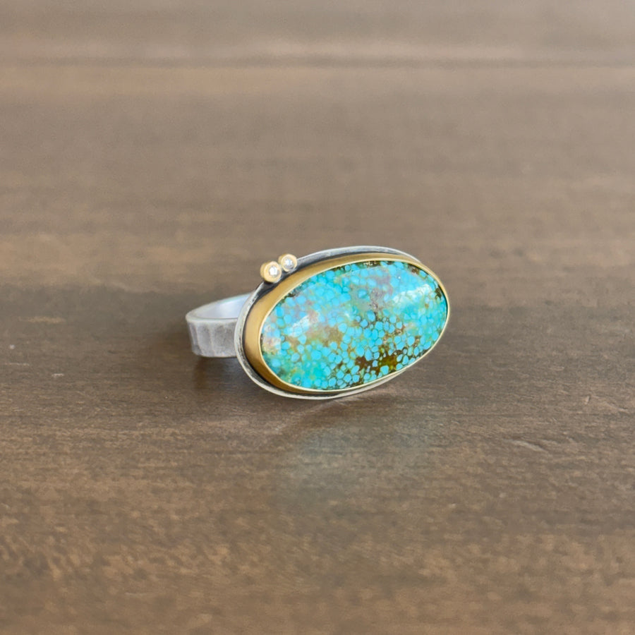 Ring with turquoise stone and gold accent on a wooden surface