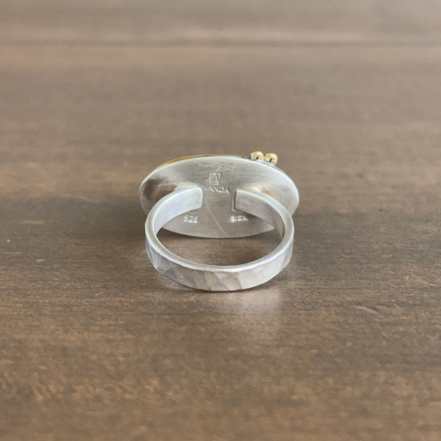 Silver ring with engraved design on a wooden surface
