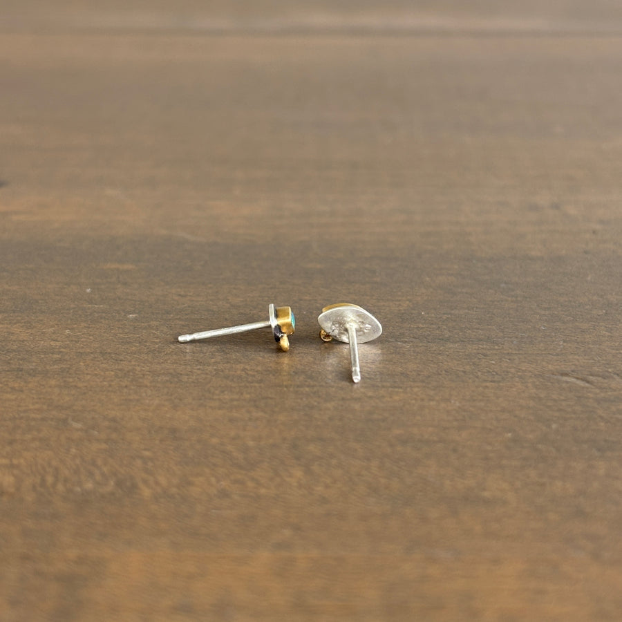 Gold and silver earring backs on a wooden surface