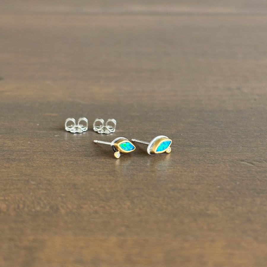 Pair of gold earrings with blue gemstones on a wooden surface