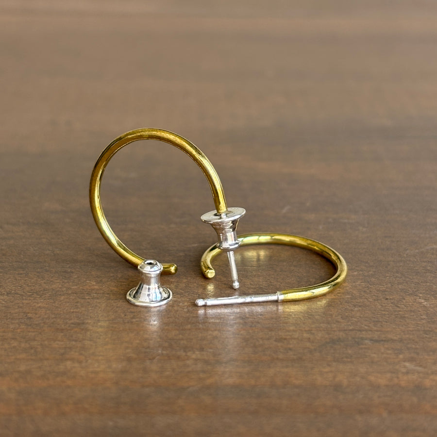 Pair of gold and silver hoop earrings on a wooden surface
