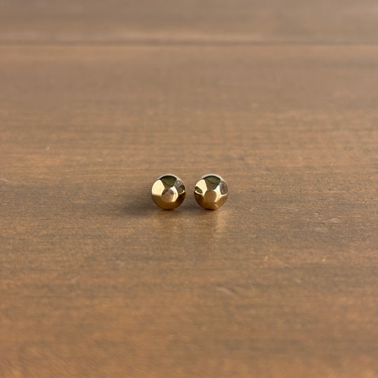 Pair of gold stud earrings on a wooden surface
