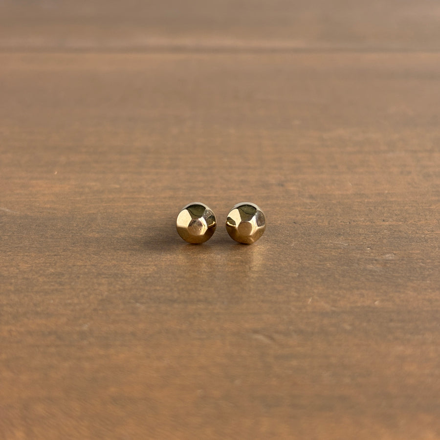 Pair of gold stud earrings on a wooden surface