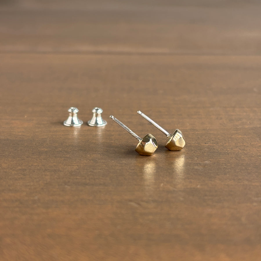 Gold and silver geometric stud earrings on a wooden surface