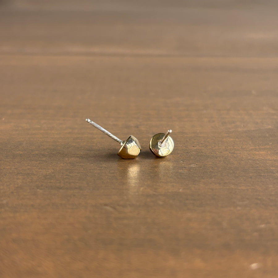 Gold geometric stud earrings on a wooden surface