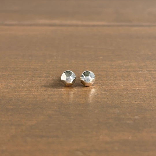 Pair of silver stud earrings on a wooden surface