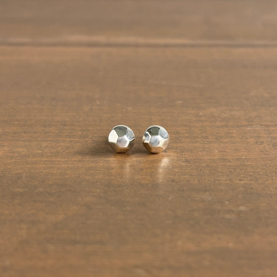 Pair of silver stud earrings on a wooden surface