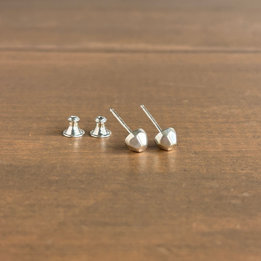 Silver geometric stud earrings on a wooden surface