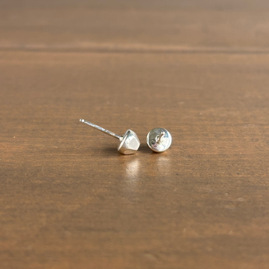 Pair of silver stud earrings on a wooden surface