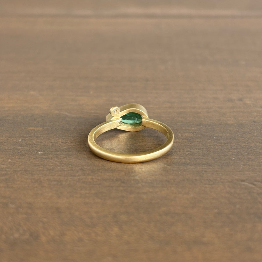 Gold ring with a green gemstone on a wooden surface
