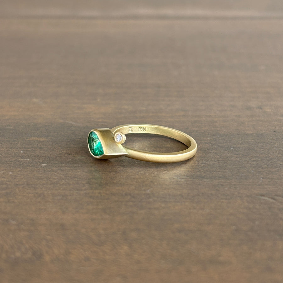 Gold ring with a green gemstone on a wooden surface