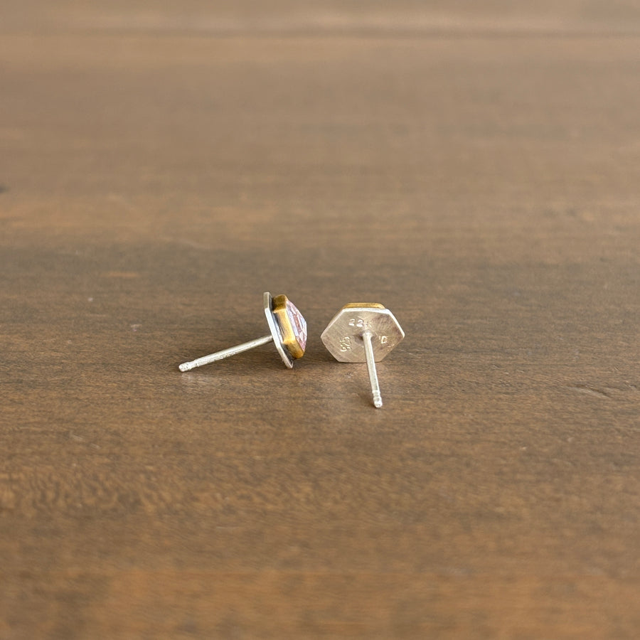 Pair of gold and silver stud earrings on a wooden surface
