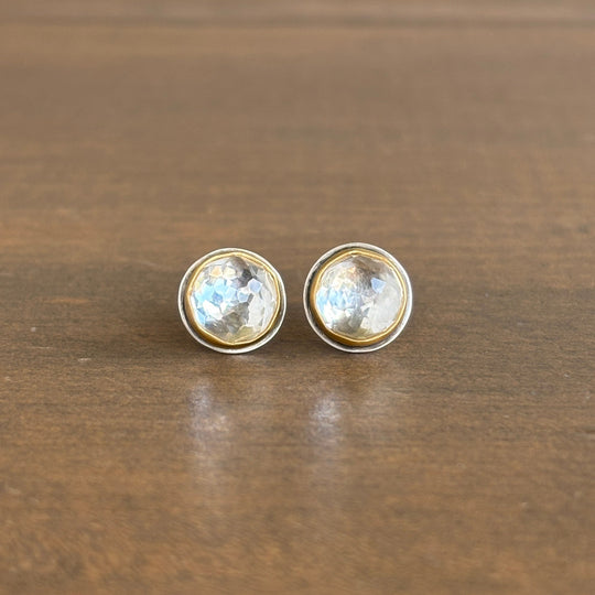 Round earrings with clear gemstones on a wooden surface