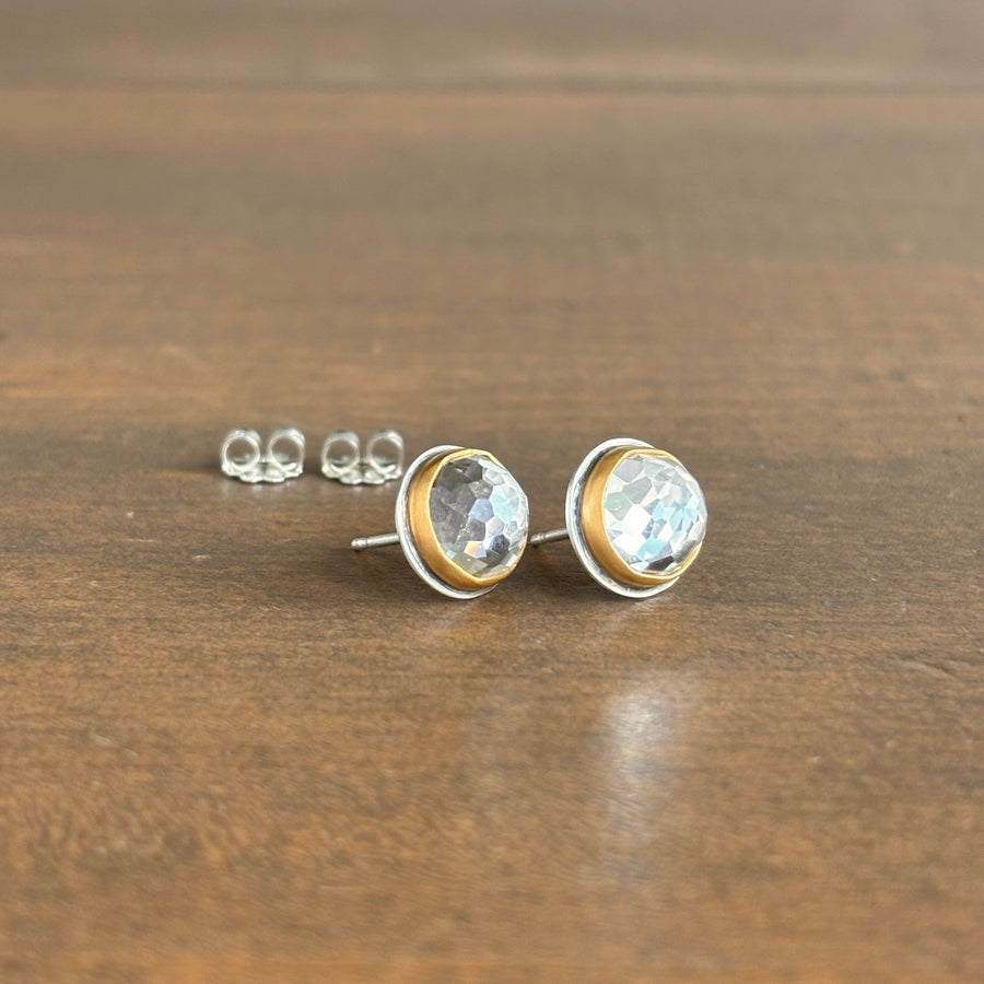 Pair of gold and crystal stud earrings on a wooden surface
