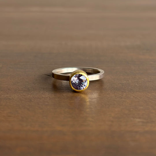 Gold ring with a clear gemstone on a wooden surface