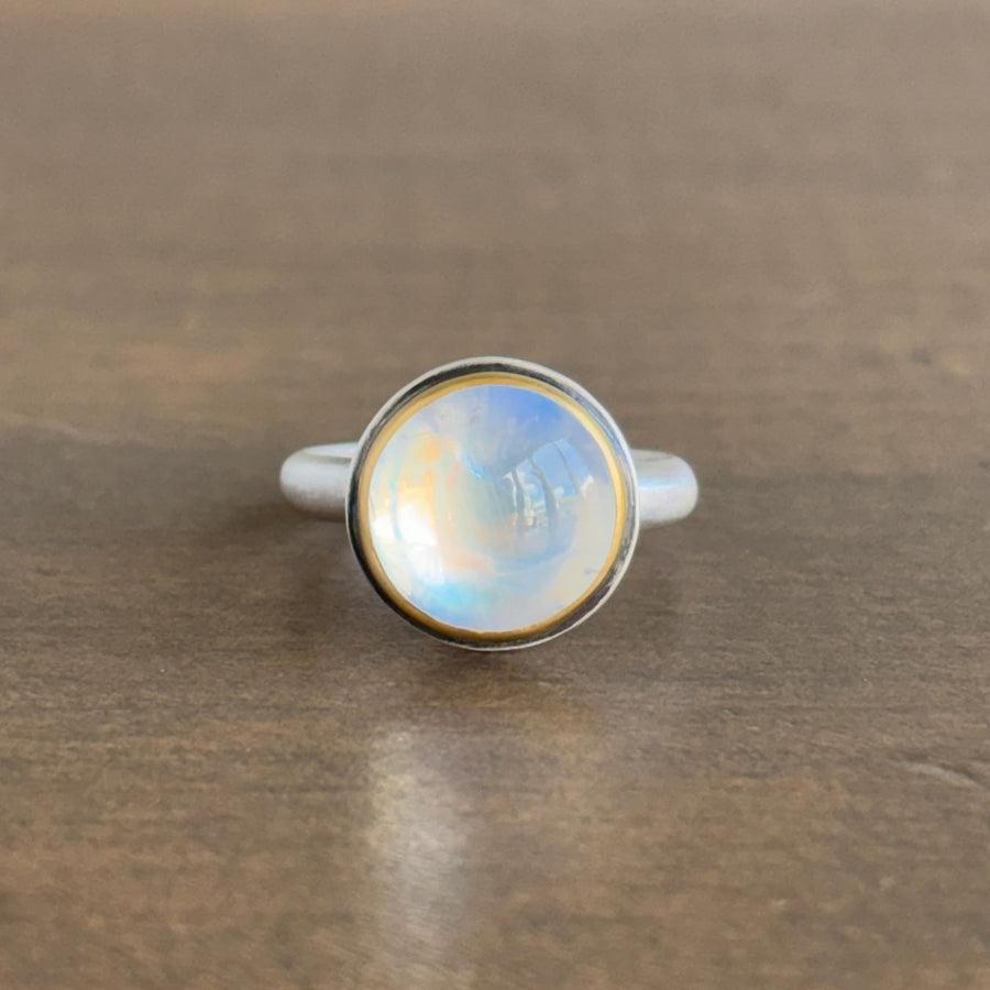 Silver ring with a round, faceted gemstone on a wooden surface