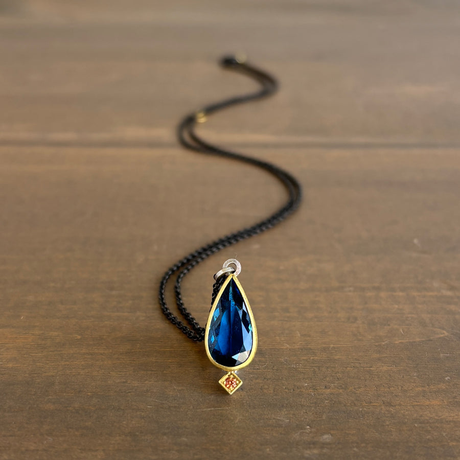Necklace with a blue teardrop pendant on a wooden surface
