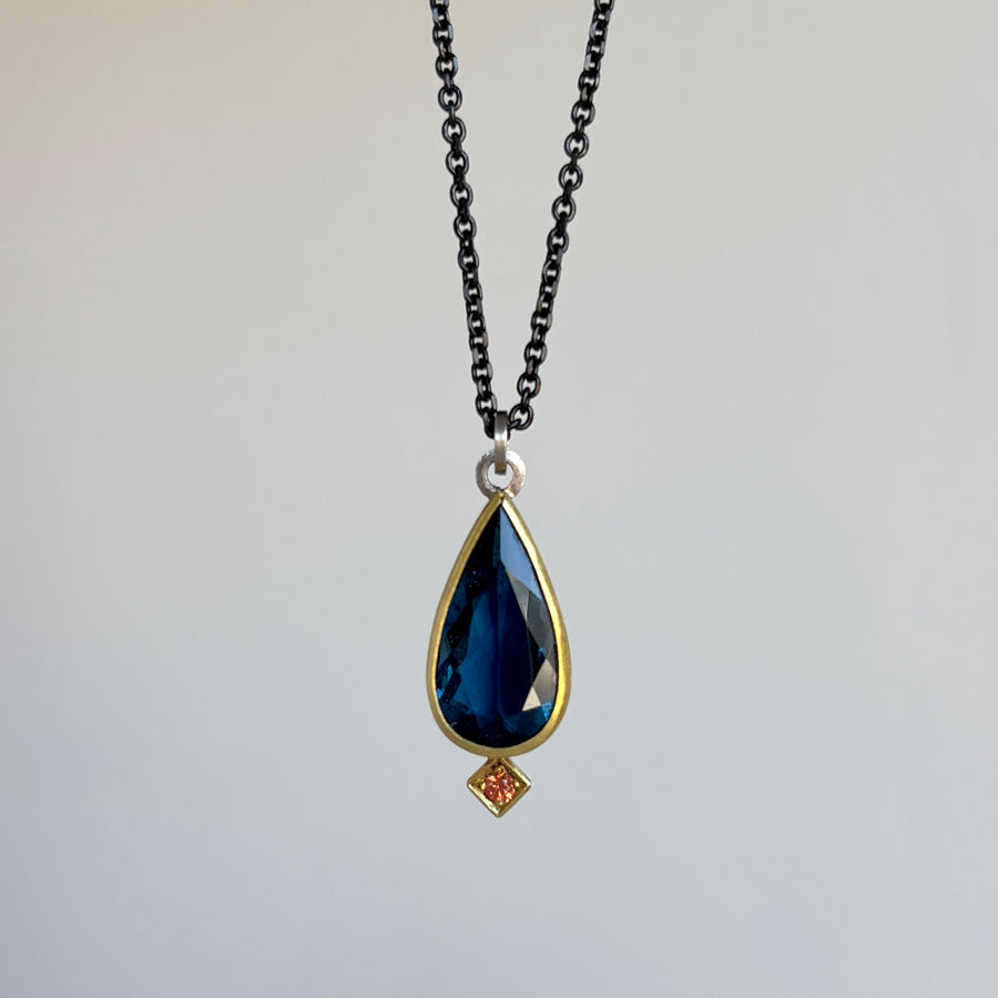 Necklace with a teardrop-shaped blue gemstone pendant on a light gray background